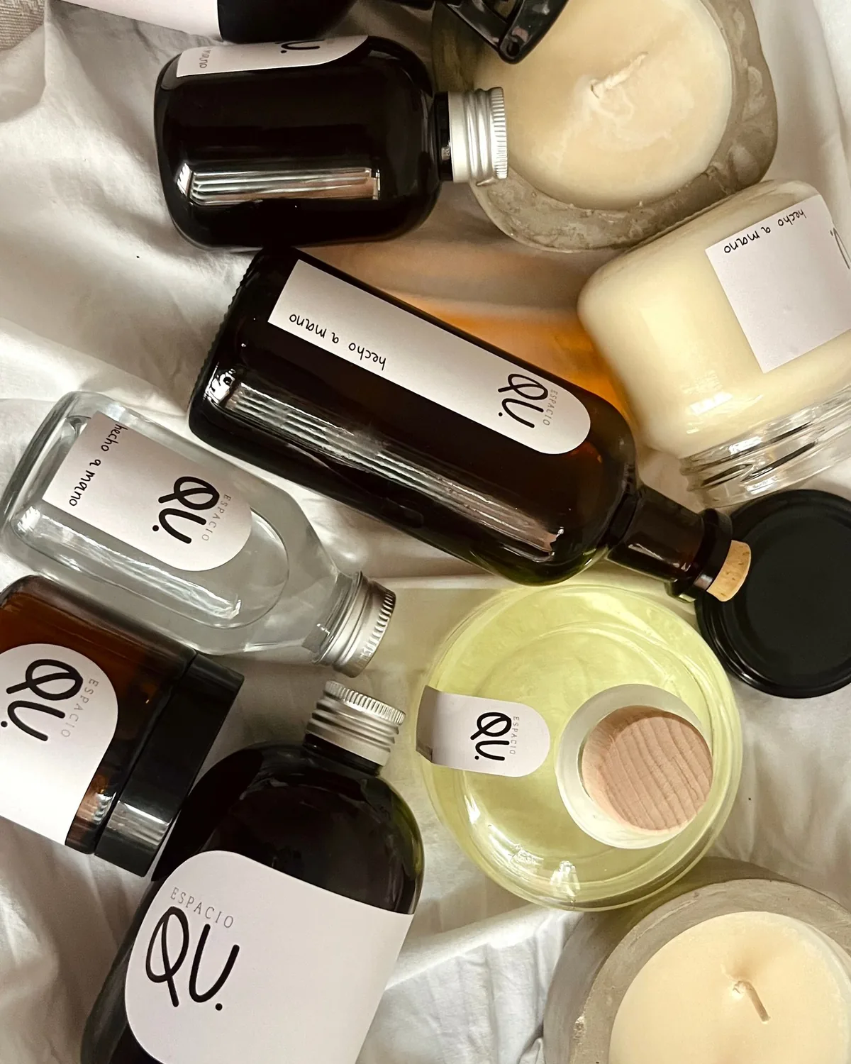 Velas, difusores y home sprays de Espacio QU sobre una sábana blanca